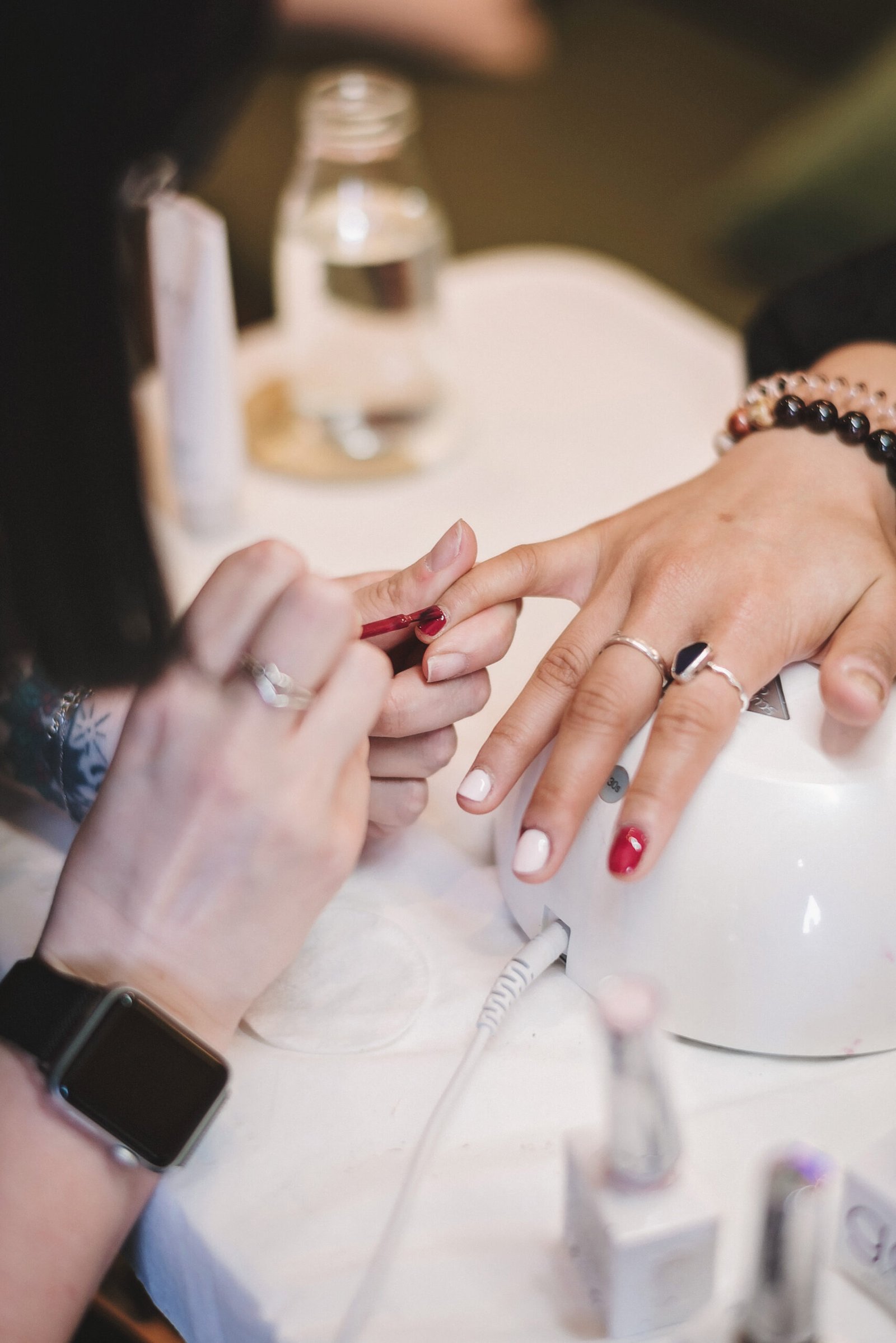 Manicure - close up of a woman getting her pinky painted with red polish